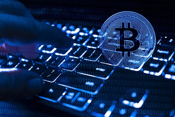 Fingers at computer keyboard and bitcoin