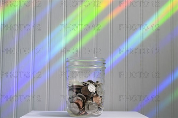 Jar of coins with rainbow light