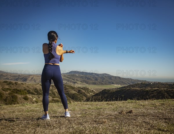 Rear view of woman stretching in landscape