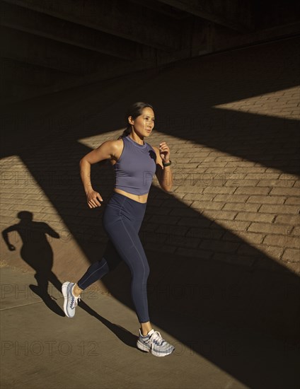 Woman jogging near brick wall in sunlight