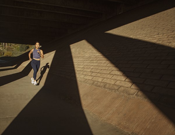 Woman jogging near brick wall in sunlight