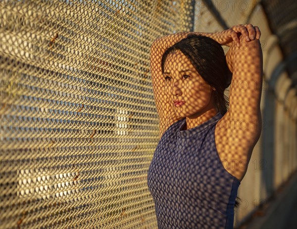 Athlete woman stretching at fence