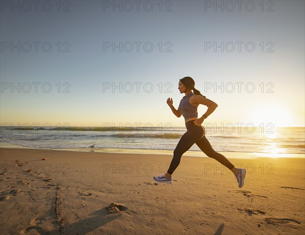 Woman jogging on beach at sunset