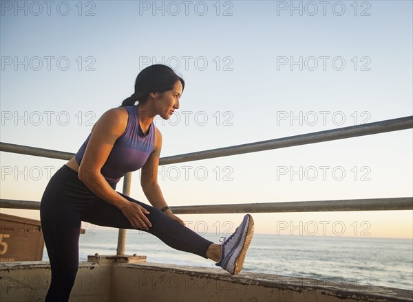 Woman stretching on beach at sunset