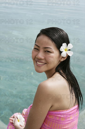 Portrait of smiling woman with frangipani flower in hair