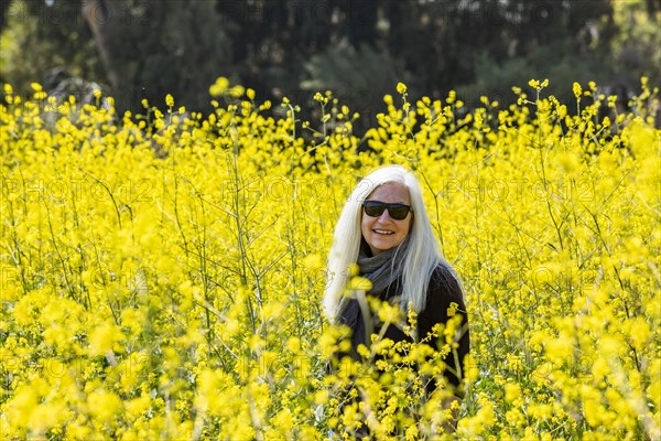 Portrait of smiling senior woman in field of wild mustard