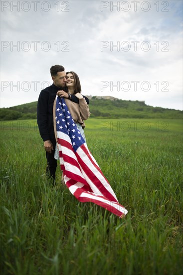 Young couple with American flag in wheat field