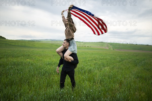 Young couple with American flag in wheat field