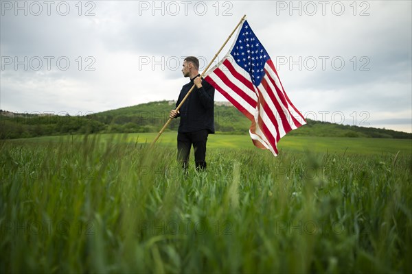 Young man with American flag in wheat field