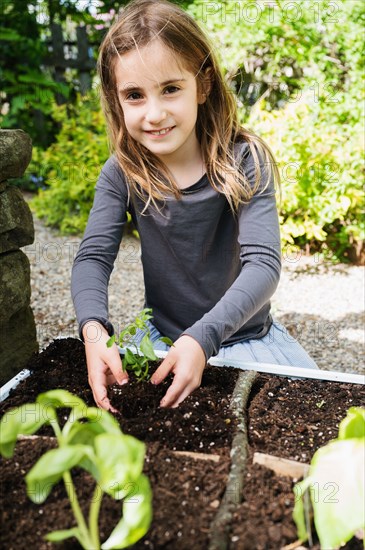 Smiling girl planting seedling