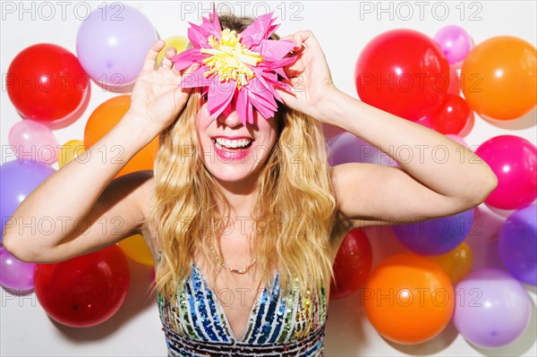 Woman holding up tissue flower in front of balloon wall