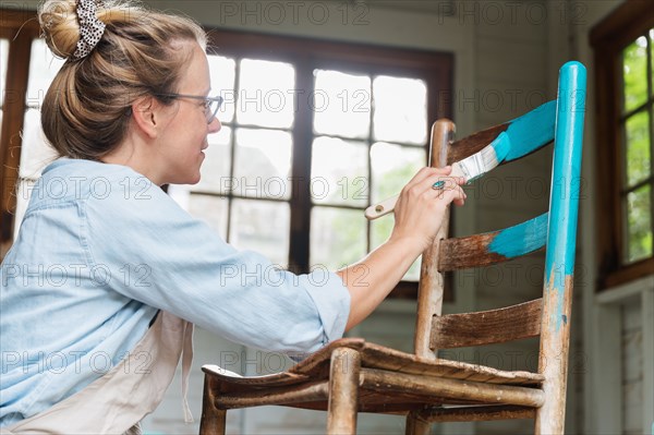 Woman painting old wooden chair