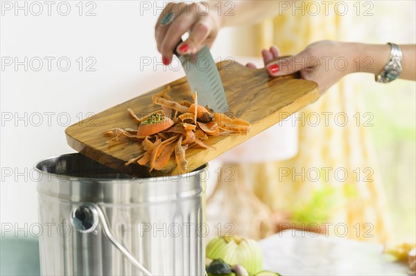 Woman putting carrot peels into compost bin