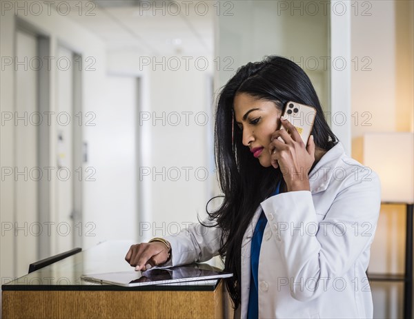 Doctor talking on mobile phone at reception desk