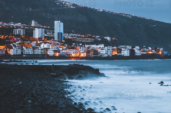 Spain, Canary Islands, Tenerife, Puerto De La Cruz, Buildings on sea coast at dusk