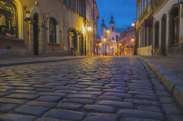 Poland, Masovia, Warsaw, Townhouses along cobblestone street in old town at night