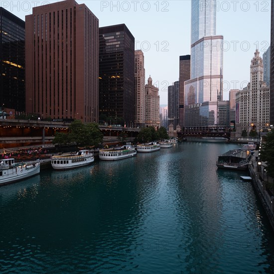 Usa, Illinois, Chicago, Downtown buildings and boats moored by river at dawn