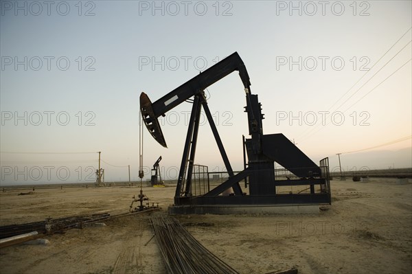 Silhouette of pump jack in oil field at sunset