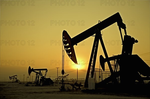 Silhouette of pump jacks in oil field at sunset