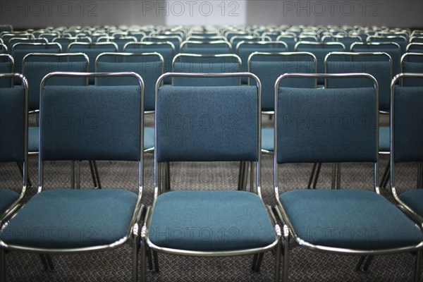 Rows of empty blue chairs in conference room