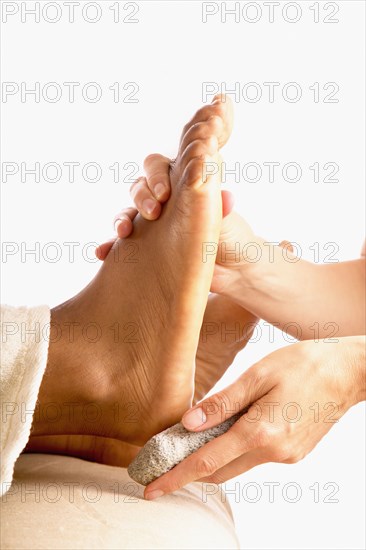 Close-up of hands using pumice stone on foot