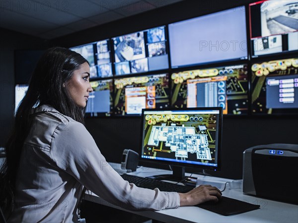 Mixed race security guard watching monitors in control room