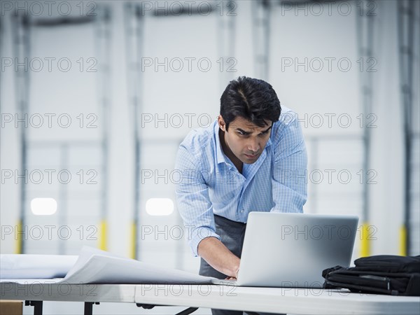 Indian architect using laptop in empty warehouse