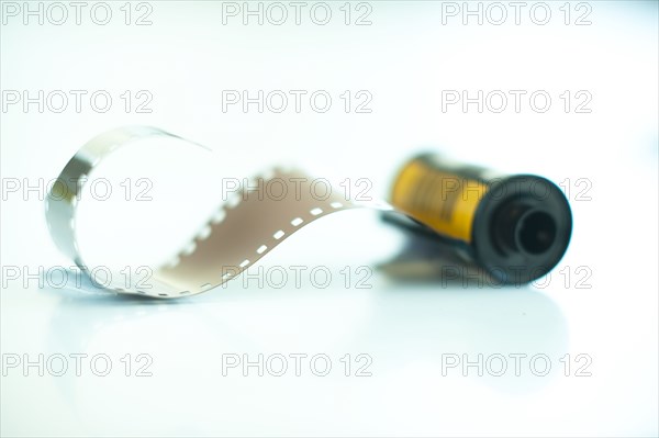 Studio shot of spool of 35mm film with some film pulled out