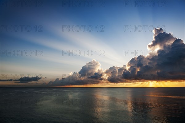 Clouds and sunlight above ocean at sunrise