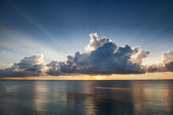 Clouds and sunlight above ocean at sunrise