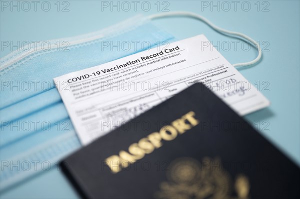 Covid-19 vaccination record card with passport and blue face mask