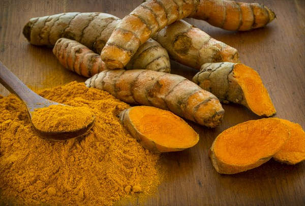 Turmeric powder and root on wooden surface