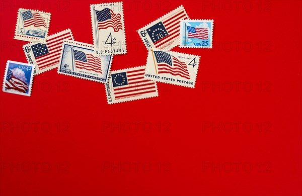 Retro postage stamps and American flag against red background