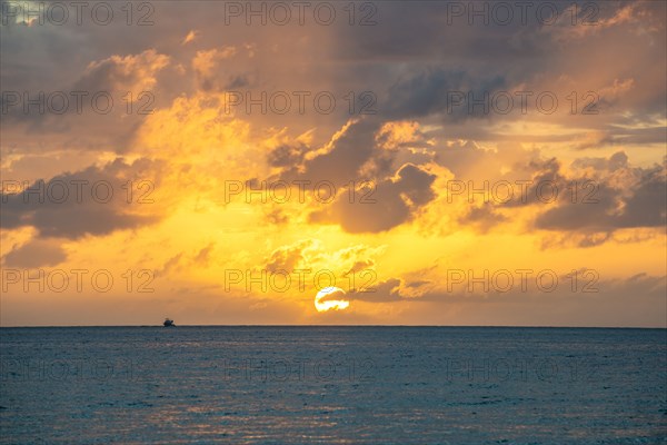 Dramatic sky at sunset over sea with fishing boat in distance