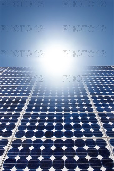 Solar panels with bright sunburst in blue sky