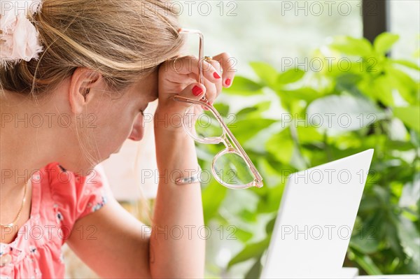 Close-up of woman at laptop resting head on hand