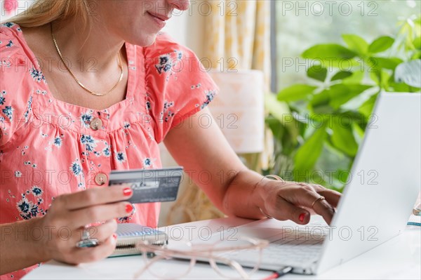 Close-up of woman at laptop shopping on-line with credit card