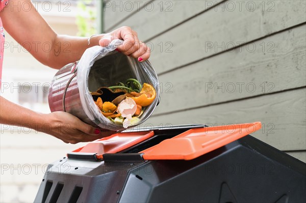 Close-up of woman putting kitchen scraps into compost bin