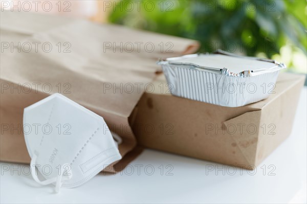 Take out food containers and face mask on table