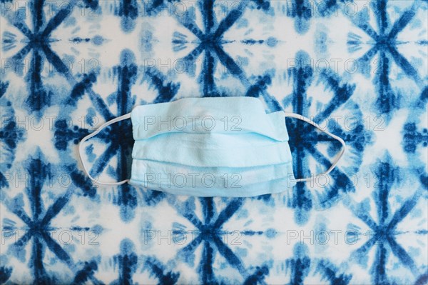 Face mask on patterned blue background