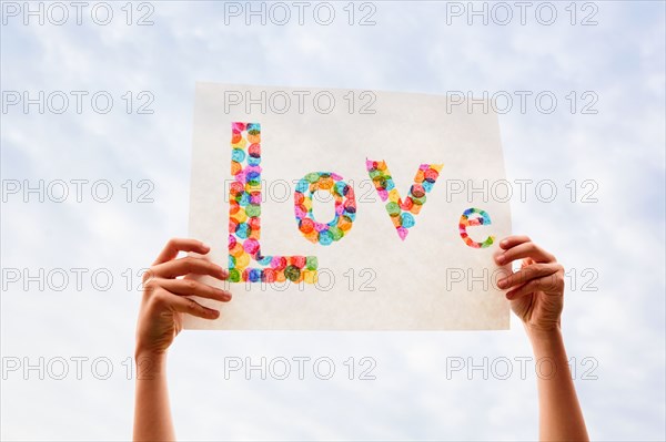 Hand of boy holding colorful Love sign