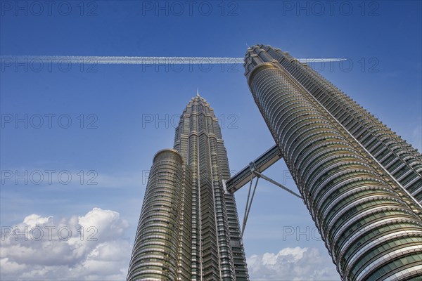 Commercial jet flying over Petronas Towers