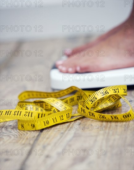 Tape measure next to woman standing on scale
