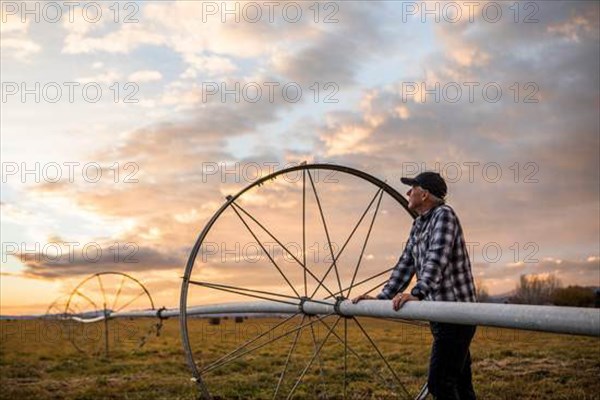 Senior man by farm sprinkler system