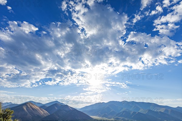 Sun and clouds over mountain landscape