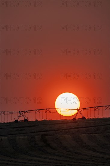 Irrigation equipment in field against setting sun