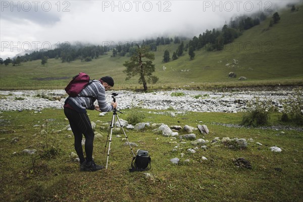 Hiker taking picture with tripod in foggy mountains