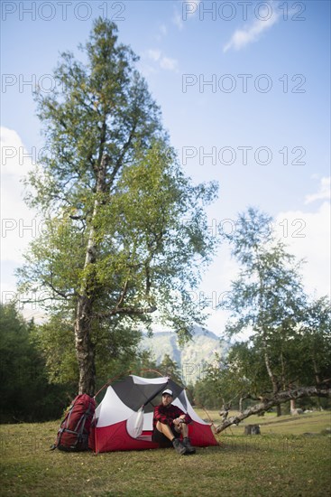 Hiker sitting by tent in mountains