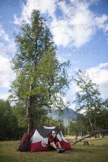 Hiker sitting by tent in mountains