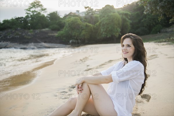 Smiling Caucasian woman sitting on beach